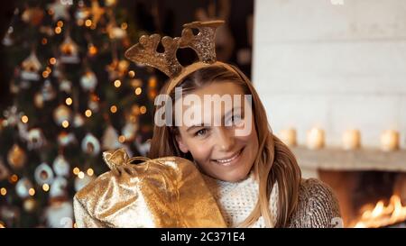 Porträt einer schönen Frau mit Freude den Winter Urlaub zu Hause, glücklich Mädchen mit Rentier Kostüm in der Nähe von geschmückten Weihnachtsbaum mit b Stockfoto