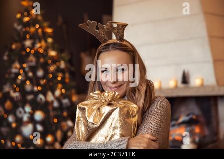 Porträt einer schönen Frau mit Freude den Winter Urlaub zu Hause, glücklich Mädchen mit Rentier Kostüm in der Nähe von geschmückten Weihnachtsbaum, holdi Stockfoto