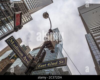 NEW YORK, USA - 18. NOVEMBER 2019: Schild für Madison Ave und East 42. Street mit Wolkenkratzern im Hintergrund und Polizeisicherheitskameras Stockfoto