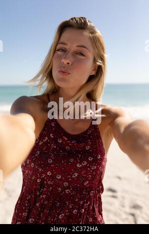 Junge kaukasische Frau nimmt Selfies am Strand Stockfoto