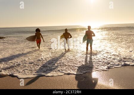 Junge Männer mit gemischtem Rennen halten Surfbretter am Strand Stockfoto