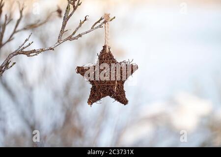 Weidenstern Weihnachtsschmuck an einem Baum an einem kalten Wintertag hängen Stockfoto