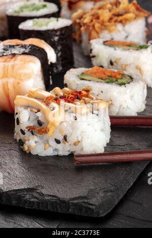 Sushi Nahaufnahme mit Essstäbchen auf schwarzem Hintergrund Stockfoto