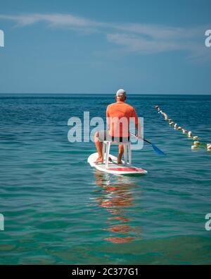 Starke Männer treiben an einem sonnigen Tag auf einem SUP-Board Stockfoto