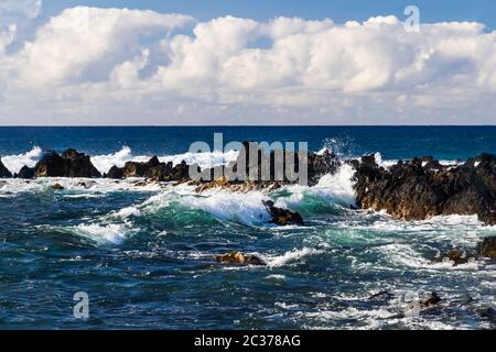 Wellen in Richtung Ufer in der Nähe von South Point, in der Hawaii Big Island rollen. Vulkanischen Felsen in der Brandung. Blauen Pazifischen Ozean erstreckt sich bis zum Horizont; overhe Stockfoto