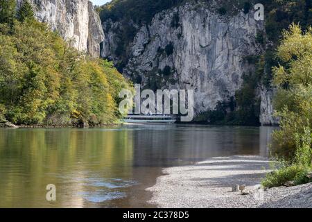 Passagierschiff, die Donau Durchbruch in der Nähe von Kelheim, Bayern, Deutschland im Herbst mit Kies bank im Vordergrund und Kalksteinformationen in der Bac Stockfoto