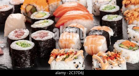 Großes Sushi-Set-Panorama, Nahaufnahme. Eine Auswahl an verschiedenen Maki, Nigiri und Brötchen Stockfoto
