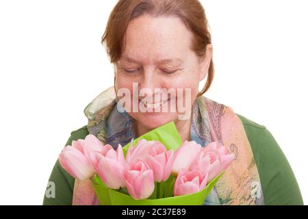 Ältere Frau hält einen Strauß von bunten rosa Tulpen, riecht und schaut nach unten, isoliert auf weißem Hintergrund. Muttertag, Stockfoto