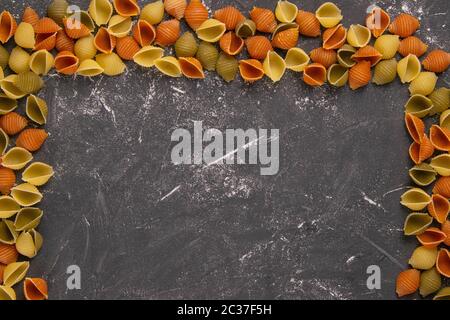 Pasta Conchiglie Rigate, Mischung aus bunten rohen Muscheln in Form eines Rechtecks mit einer leeren Mitte. Strukturiertes italienisches Food Hintergrundkonzept. T Stockfoto