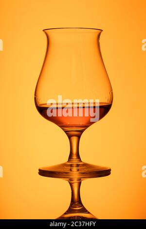 Glas mit Orange Whisky in der Rückseite mit Reflexion lit Stockfoto