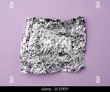 Zerknitterte Folie verwendete Süßigkeiten-Wrapper auf einem lilafarbenen Hintergrund, Draufsicht Stockfoto