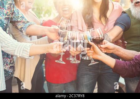 Fröhliche Familie mit Rotweingläsern beim Abendessen im Freien - Leute, die Spaß haben, beim gemeinsamen Essen zu jubeln und zu trinken Stockfoto