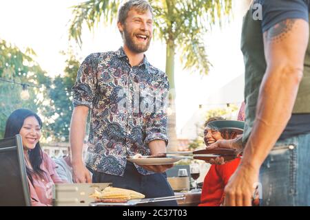 Glückliche Familie, die Spaß an der Grillparty - Chef Senior Mann Grillen und servieren Fleisch Stockfoto