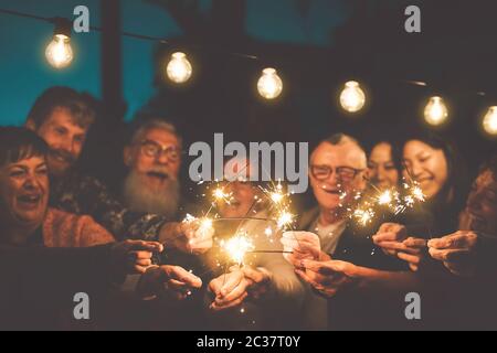 Glückliche Familie feiert Silvester mit Sparkler Outdoor - Gruppe Menschen mit verschiedenen Alters und Ethnizität Spaß zusammen in der Nacht Party Stockfoto