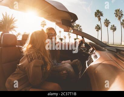 Glückliches junges Paar macht einen Ausflug in die tropische Stadt - Reisen Sie Leute, die Spaß haben, mit dem trendigen Cabrio-Auto zu fahren und neue Orte zu entdecken Stockfoto