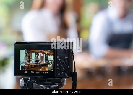 VLOG von jungen erwachsenen Asiatischen Eigentümer Unternehmer bewerten cafe Coffee Shop und Leben in sozialen Medien für Online Marketing mit Kamera im Cafe. Verwendung für Sta Stockfoto