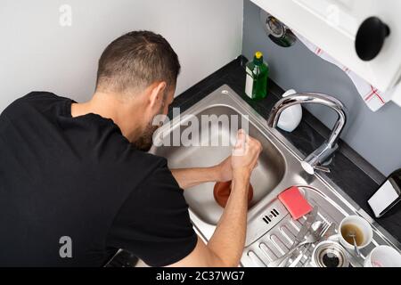 Reinigen Von Verstopften Abflussverstopfungen Im Küchenwaschbecken Mit Stößel Stockfoto
