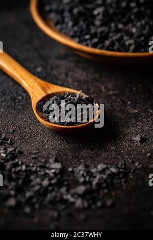 Meersalz wird von der vulkanischen Lava schwarz gefärbt und mit deaktivierter Holzkohle auf dunklem Hintergrund vermischt Stockfoto