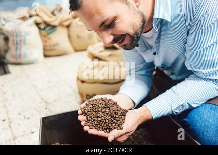 Mann mit frisch gerösteten Kaffeebohnen in der Hand Stockfoto