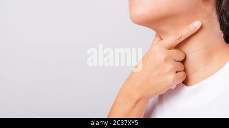Asiatische schöne Frau Schmerzt Hals oder Schilddrüse Problem ihre ausierende Hand Berührt Kranken Hals auf weißem Hintergrund mit Kopierraum, Medical und Healthca Stockfoto