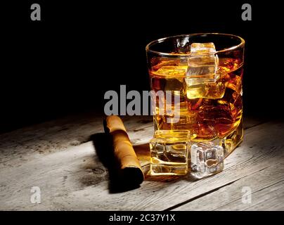 Glas im Alter von Whiskey mit Zigarre und Eiswürfeln auf Holztisch Stockfoto