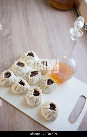 Der Prozess der Home - Knödel gemacht. Raw hausgemachte Knödel auf einem Holzbrett. Knödel formen. Stockfoto