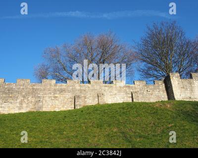 Ein Blick auf die alten mittelalterlichen Stadtmauern von york mit Gras bedeckt Böschung und blauen Himmel Stockfoto