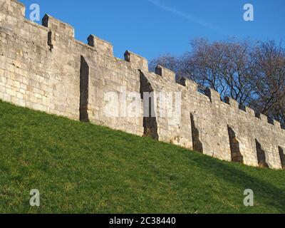 Ein Blick auf die alten mittelalterlichen Stadtmauern von york mit Gras bedeckt Böschung und blauen Himmel Stockfoto