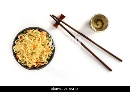 Sofort-Nudeln-Schüssel mit Karotten und Hengsten, mit Essstäbchen und Sake, von oben auf weißem Hintergrund geschossen Stockfoto