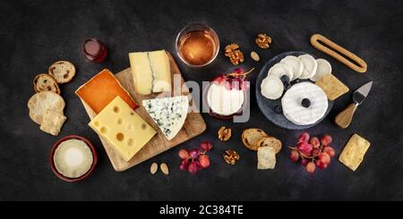 Käsevielfalt Panorama mit Wein und Obst, flacher Lay, obenliegender Schuss auf schwarzem Hintergrund Stockfoto