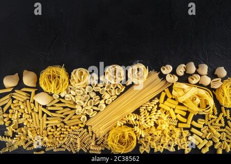 Italienische Pasta-Textur mit einem Ort für Text, ein Flatlay von vielen verschiedenen Pasta-Typen, von oben auf einem schwarzen Hintergrund mit aufgenommen Stockfoto