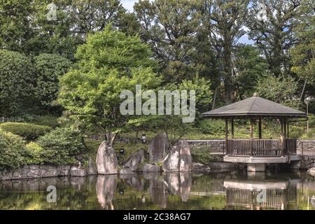 Hexagonal Pavillon Ukimido in der Mitte Teich Mejiro Garten, wo Karpfen schwimmen und die ist umgeben Stockfoto