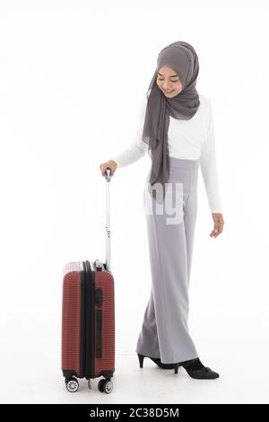 Voller Körper Portrait von glücklichen asiatischen muslimischen Touristen Frau mit Hijab halten roten Koffer Gepäck erhalten für Reisen und Reise bereit. Studio shot Stockfoto