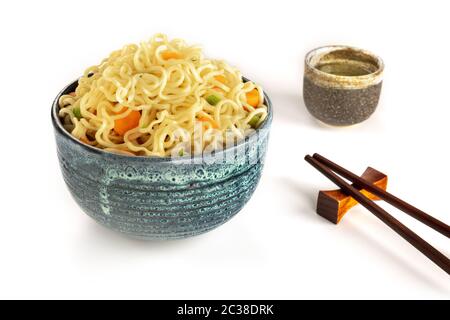 Nudelschüssel mit Karotten und Hengsten, Gemüsesoba mit Essstäbchen und Sake auf weißem Hintergrund Stockfoto