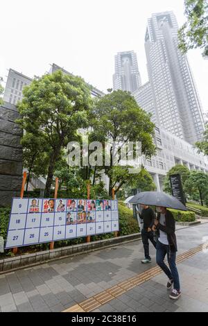 Fußgänger kommen an einem Plakatbrett vorbei, das mit Plakaten für die bevorstehenden Gouverneurswahlen in Tokio nahe dem Gebäude der Tokyo Metropolitan Government am 19. Juni 2020 in Tokio, Japan, aufgestellt wurde. Die Kampagne begann offiziell am Donnerstag, 18. Juni, und wird am 5. Juli stattfinden. Quelle: Rodrigo Reyes Marin/AFLO/Alamy Live News Stockfoto