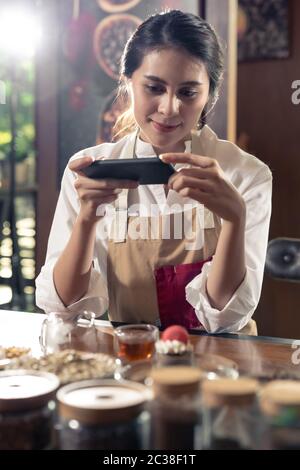 BLOGGER von jungen erwachsenen Asiatischen Eigentümer Unternehmer bewerten cafe Coffee Shop für Social Media und Online Marketing im Cafe. Mit Hilfe bei der Inbetriebnahme von kleinen Busi Stockfoto