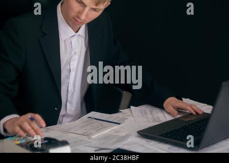Weißer Mann, der in einem Büro mit Dokumenten arbeitet. Der Manager erstellt den Bericht und füllt die Erklärung aus. Geschäftsmann bei der Arbeit an seinem Arbeitsplatz. Jung Stockfoto