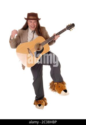 Ein mittleres Alter indigener in schicken Schuhen tanzen und seine Gitarre spielen in einer Jacke und Hut, auf weißem Hintergrund Stockfoto