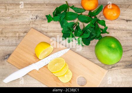 Zitronen mit Minze und Orangen auf einem Holzbrett in Scheiben geschnitten Stockfoto