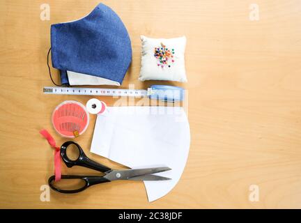 Tischansicht der Nähausrüstung, um Ihre eigenen schützenden Coronavirus Gesichtsmaske, Holzhintergrund, Nadelcraft DIY-Projekt zu machen. Stockfoto