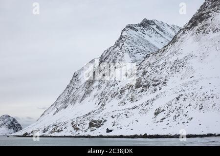 Ein verschneite Berg am Haukland Strand in Lofoten. Stockfoto