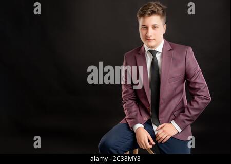 Portrait des Jurastudenten mit blonden Haaren in Burgunderjacke gekleidet, weißes Hemd und schwarze Krawatte posiert auf isoliertem Hintergrund mit Copy Space advertin Stockfoto