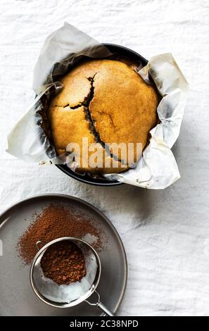 Frisch zubereiteten Kaffee Kuchen in eine Springform geben durch ein Sieb Stockfoto