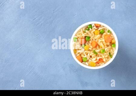 Ramen Tasse, Soba-Nudeln mit Karotten und grünen Erbsen in einem Plastikbecher, Top-Shot mit Kopierraum Stockfoto
