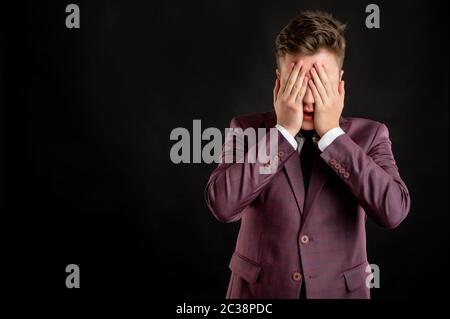 Jurastudent mit blonden Haaren in Burgunder Jacke, weißes Hemd und schwarze Krawatte über Auge wie blind Konzept posiert auf isoliertem schwarzen Hintergrund gekleidet Stockfoto