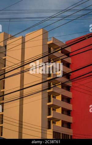 Viele Telefonstromkabel kreuzen sich vor dem neu erbauten, sonnendurchfluteten, utilitaristischen Apartmentblock, Merida, Mexiko Stockfoto