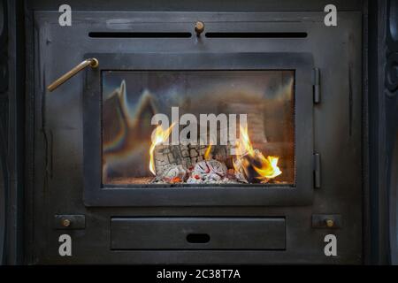 Traditionelle schwarze Holzofen close-up mit Feuer flammen, Antik gemütliche Stockfoto