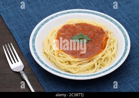 Pasta-Spaghetti mit Tomatensauce und Basilikum auf weißem Hintergrund auf dem Esstisch Stockfoto