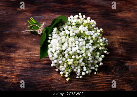 Zartes Bouquet der Maiglöckchen auf einem hölzernen Tisch. Blumenstrauß für den Urlaub. Selektiver Fokus. Stockfoto