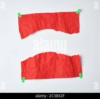 Zerknitterte rotes Blatt A4-Papier zur Hälfte abgerissen und mit grünem Klebeband auf einem weißen Hintergrund geklebt, Element für einen Designer Stockfoto